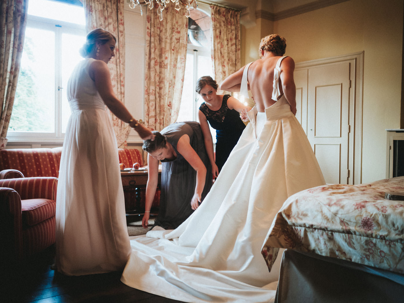 Bride getting dressed with her bridesmaids - wedding photos Schloss Saareck