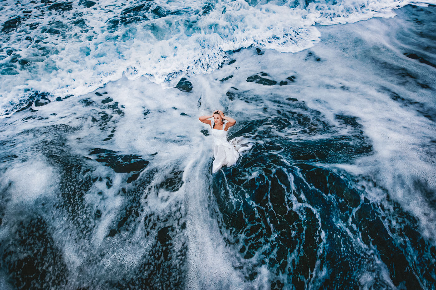 Bride in wedding dress standing in the waves of the Atlantic, birds-eye-view showing wonderful patterns in the water, After-Wedding-Session at Slea Head, Dingle, Co. Kerry, Ireland