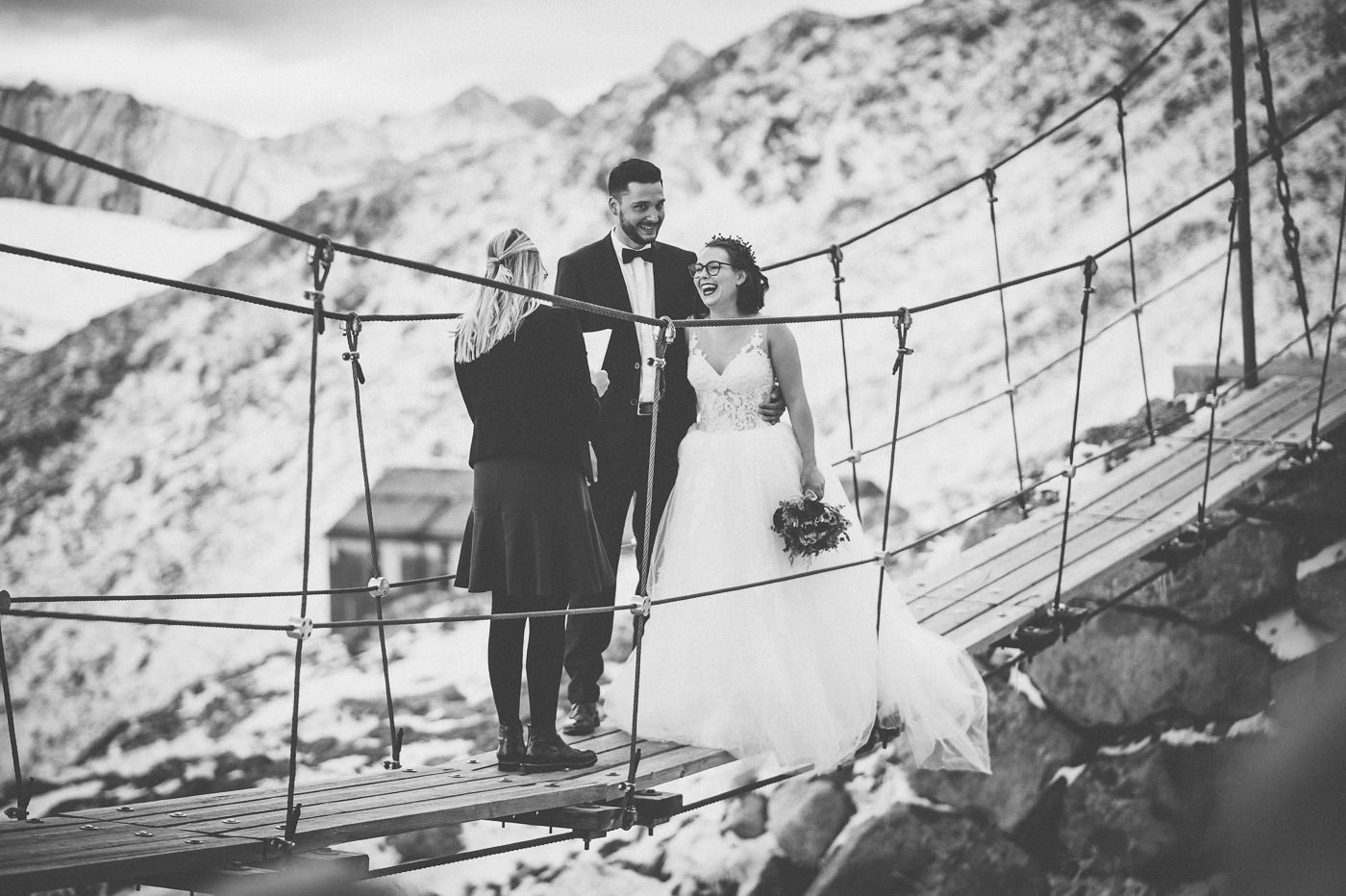 Schwarzweißfoto von lachendem Brautpaar während einer freien Trauung auf der Hängebrücke an der Olpererhütte in den Zillertaler Alpen
