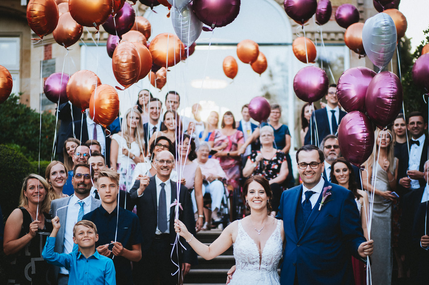 Gruppenfoto von Hochzeitsgesellschaft mit Brautpaar und Ballons vor der Villa Rothschild - Hochzeitsfotograf Taunus Brautrausch