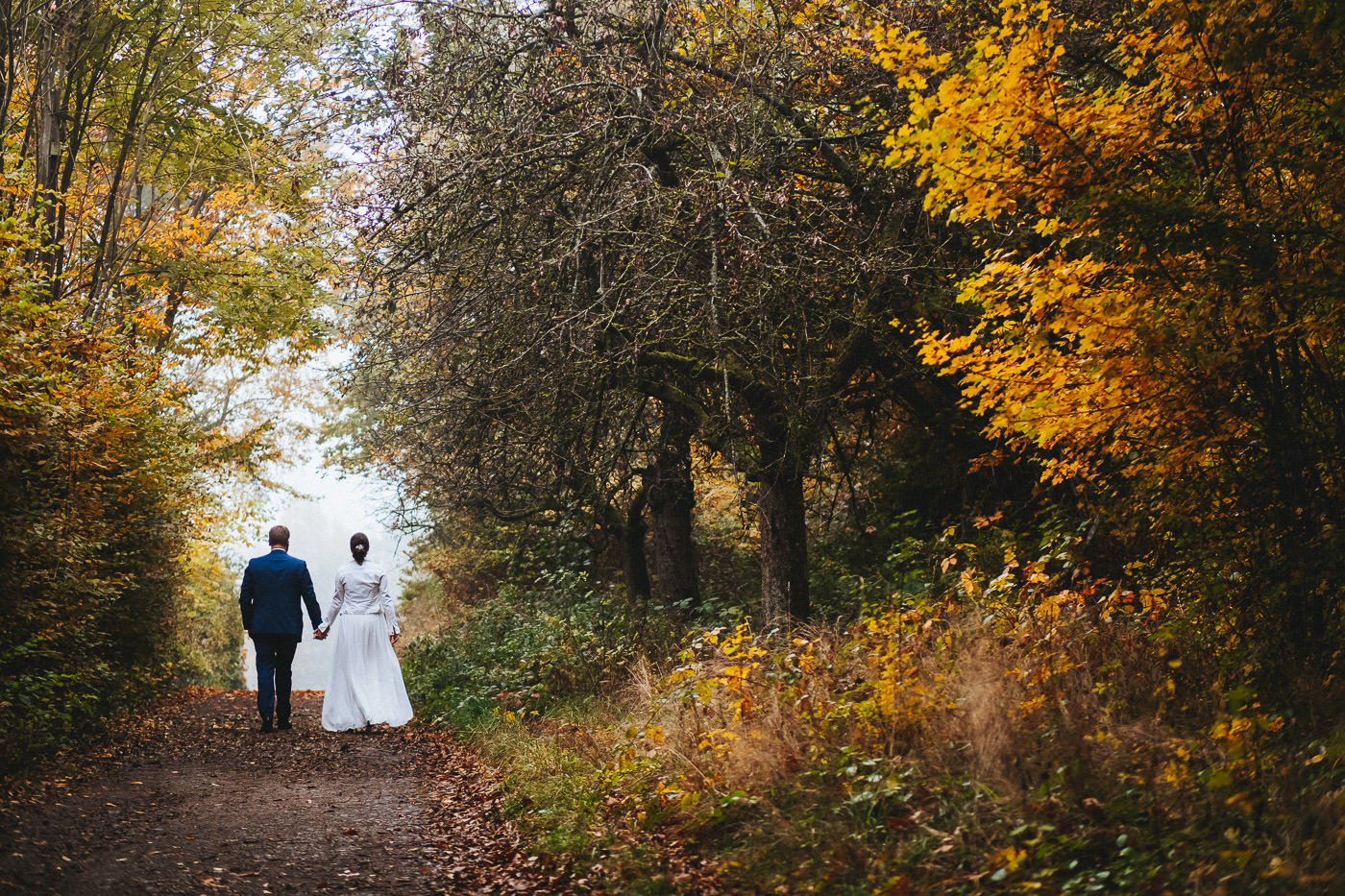 Brautpaar spaziert händchenhaltend durch herbstlichen Wald - Hochzeitsfotograf Taunus Brautrausch