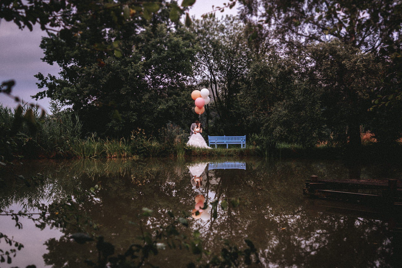 Brautpaar mit Ballons am Teich der Hochzeitslocation Hofgut Georgenthal