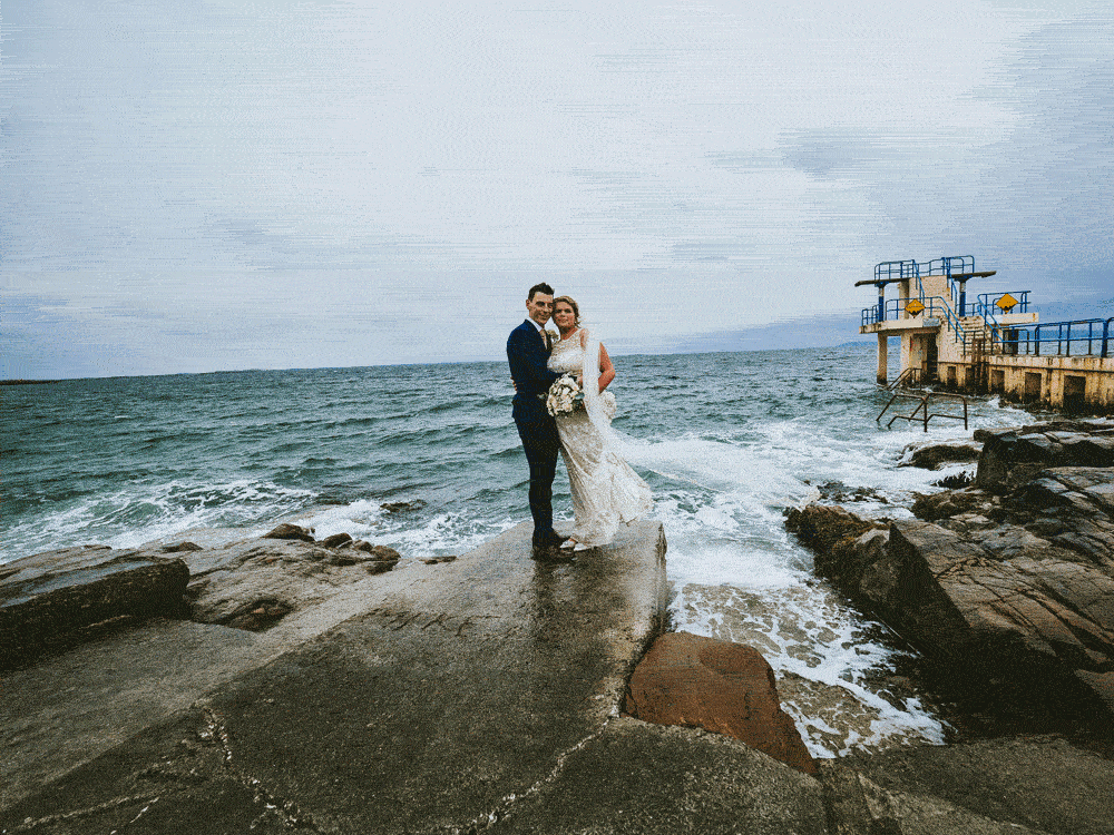 Animiertes Hochzeitsfoto (GIF) mit Brautpaar am Blackrock Beach in Galway und einem Schwimmer der quer durchs Bild läuft
