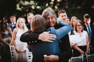 Brautvater umarmt Bräutigam vor der freien Trauung im Garten der Villa la Massa - Hochzeitsfotos in der Toskana