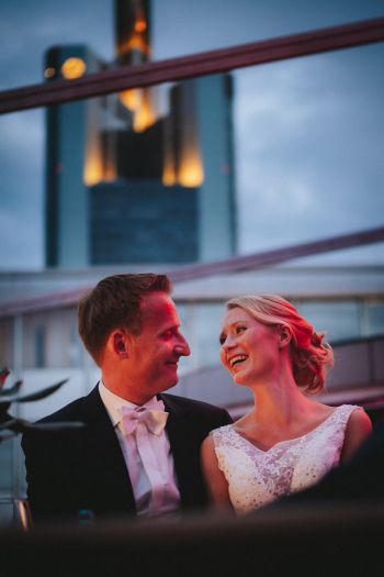 Schwules Brautpaar stößt mit Sektflaschen im Bett an, zusammen mit 3 Bridesmaids in Brautkleidern und 4 Groomsmen - eine Zimmerparty auf einer Suite im Schlosshotel Kronberg, aufgenommen im Rahmen einer Hochzeitsreportage im Schlosshotel - Hochzeitsfotograf Taunus Brautrausch