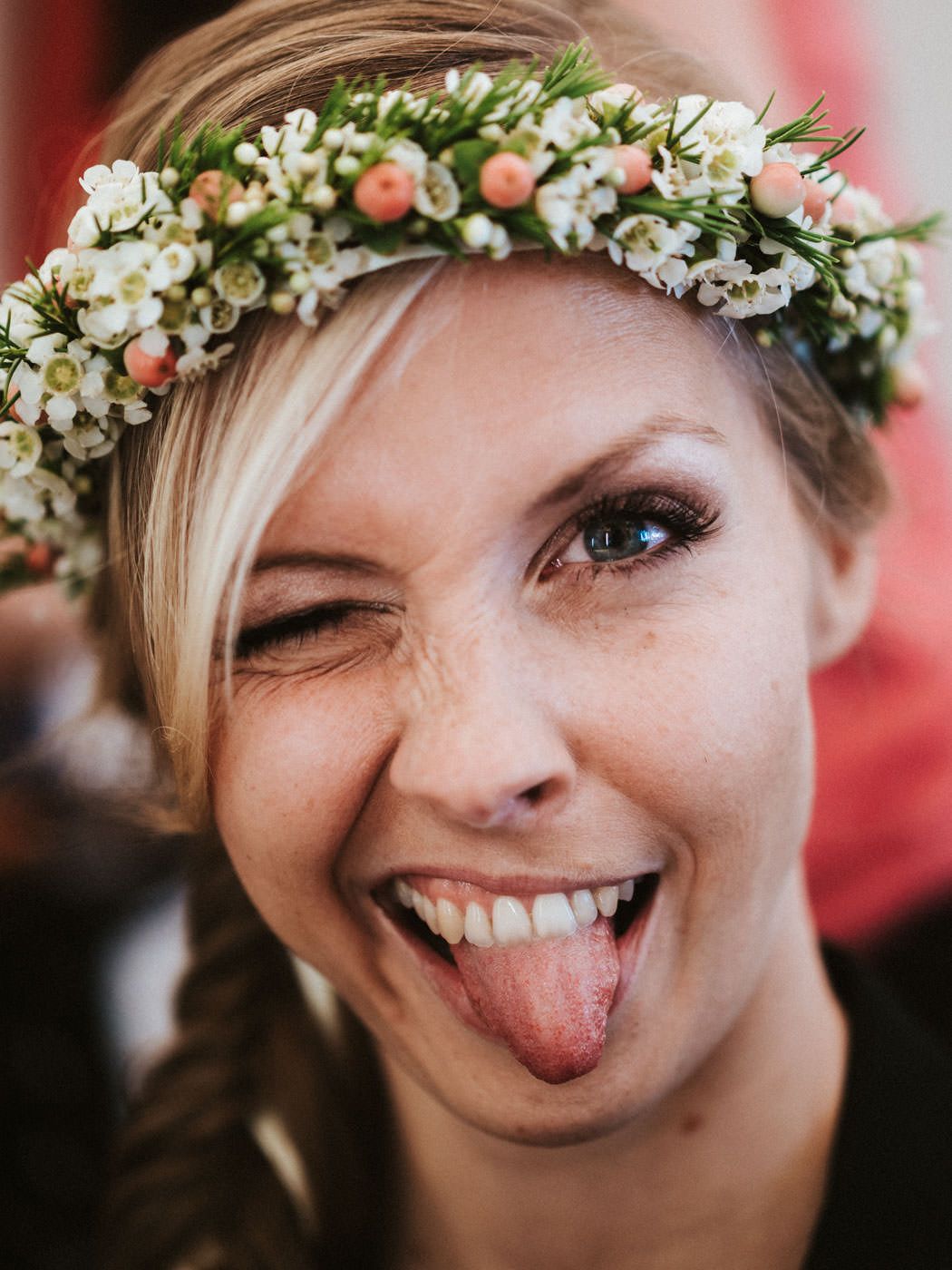Braut mit rausgestreckter Zunge und Kranz im Haar - Getting Ready für die Hochzeit im Weingut Weidenmühle