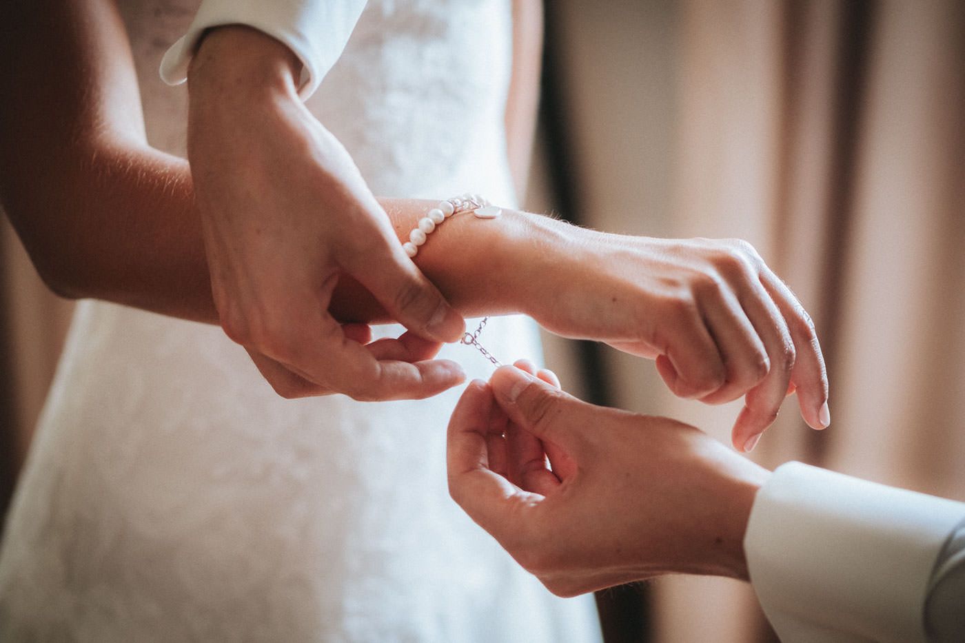 Bride in wedding dress putting on a bracelet for her wedding