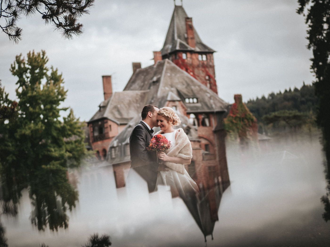 Brautpaar mit Schloss Saareck im Hintergrund - Hochzeitsfotos Schloss Saareck