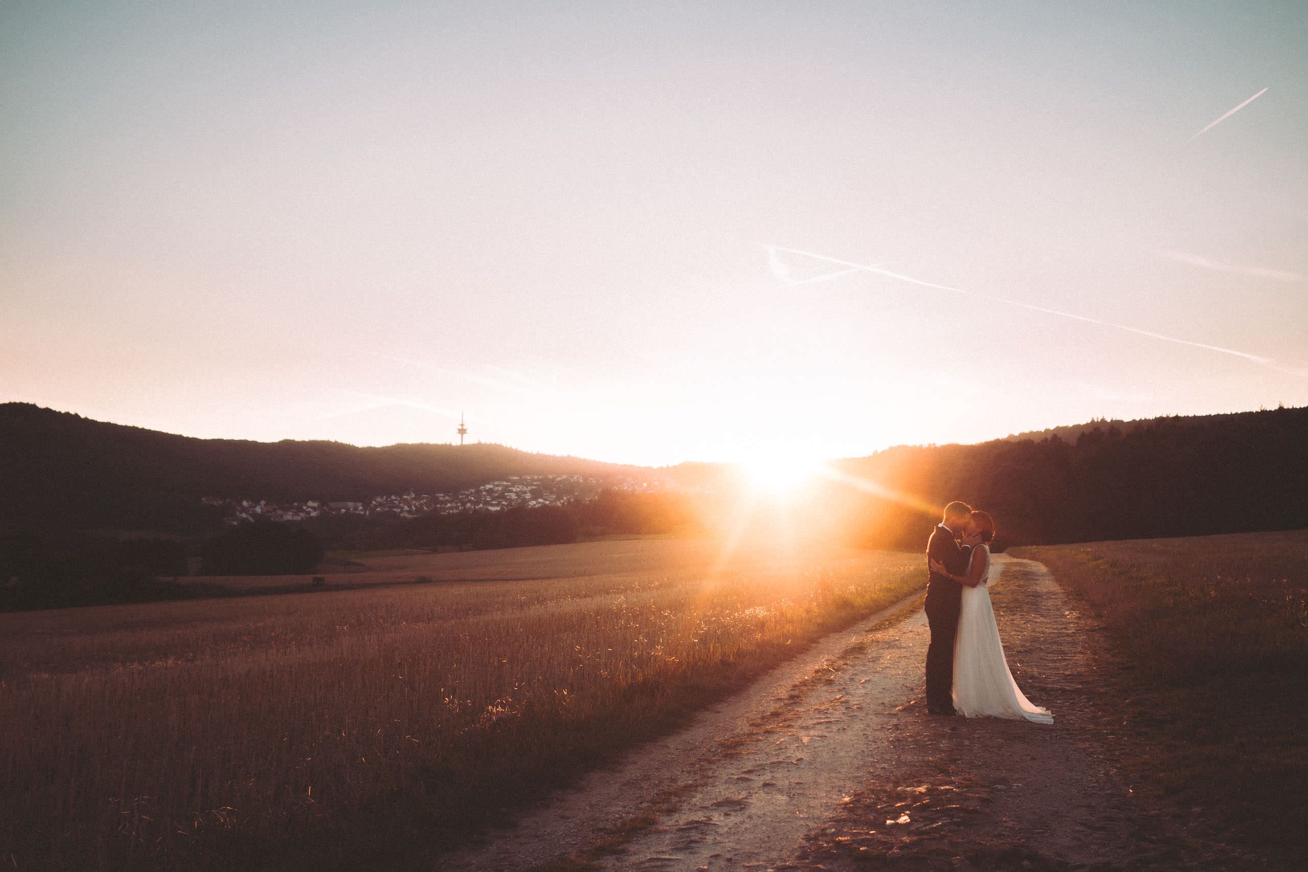 Brautpaar im Gegenlicht eines Sonnenuntergangs mit Taunuskamm im Hintergrund - Hochzeitsfotograf Taunus Brautrausch