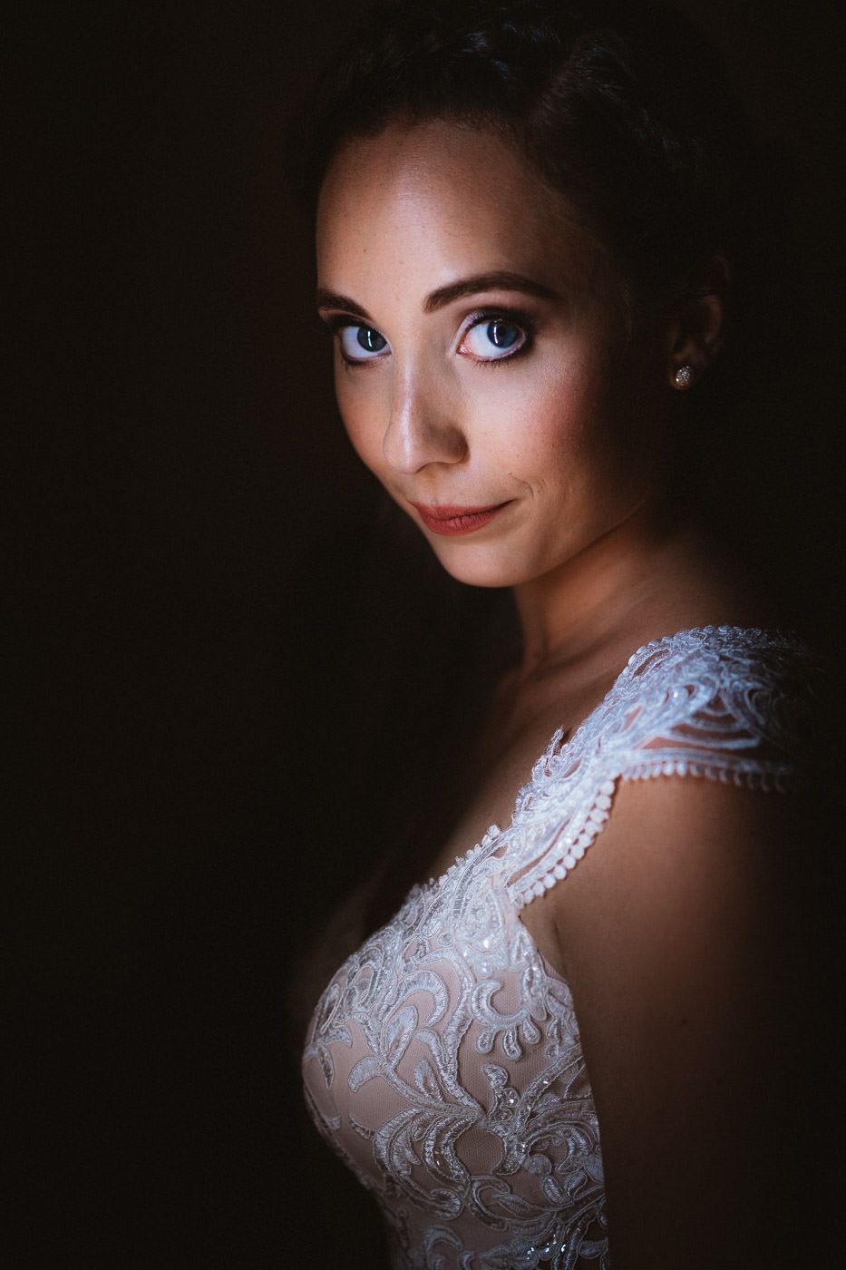 Bride looking at the camera, dramatically lit by window light.