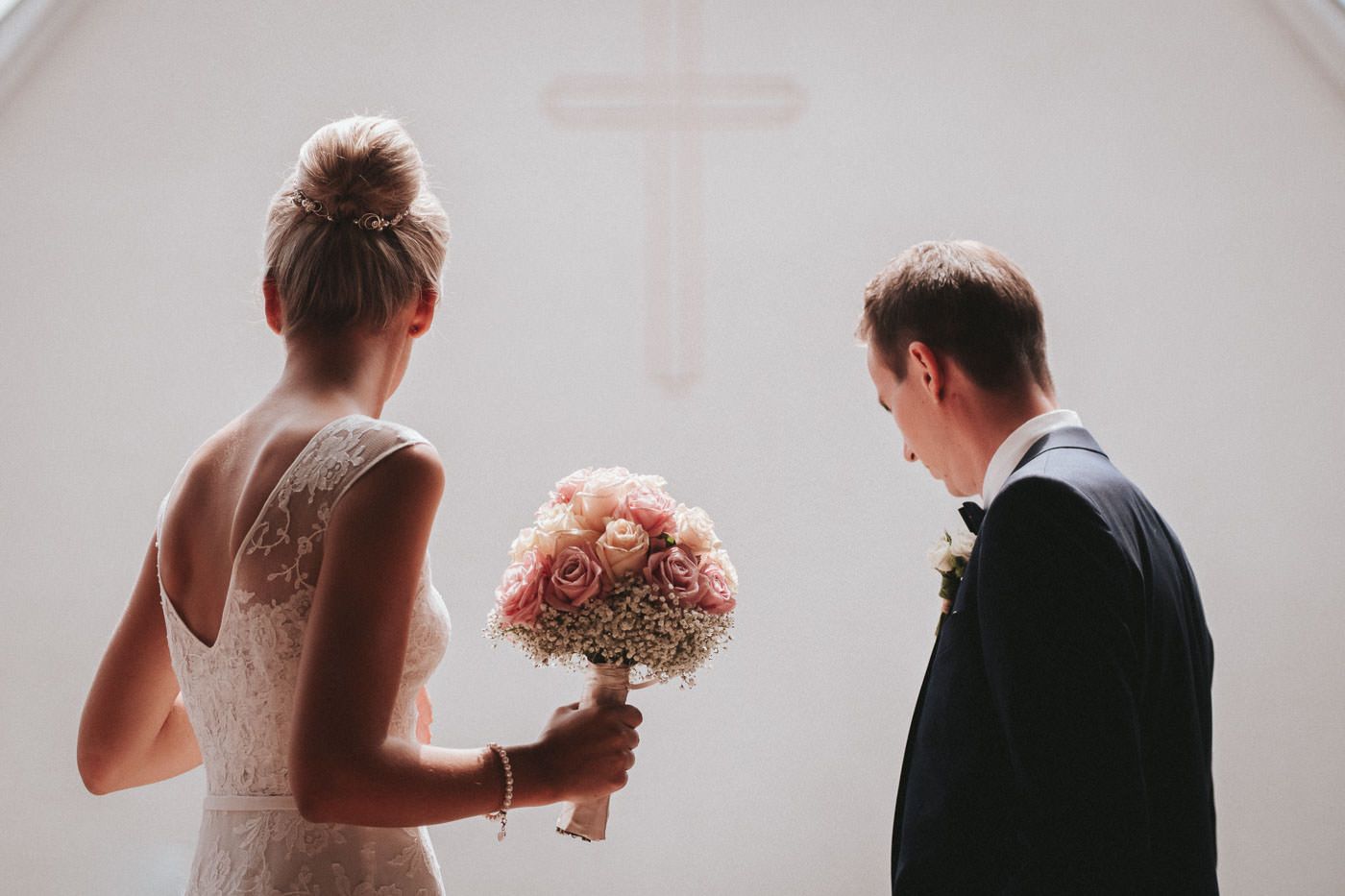 Bridal couple waiting in front of the church, bride holding the wedding bouqet