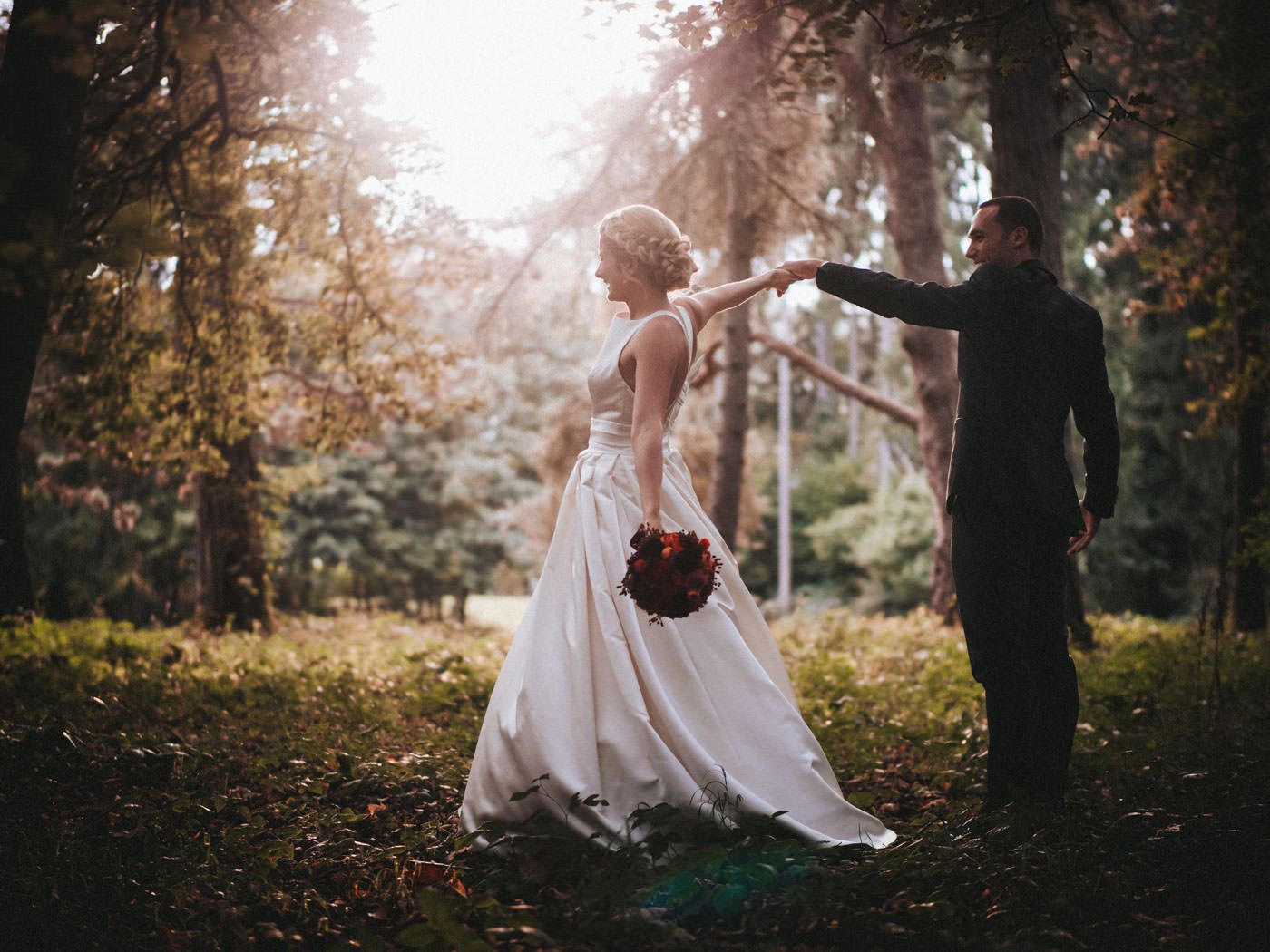 Brautpaar tanzend im Wald mit Gegenlicht von der schon tiefstehenden Sonne- Hochzeitsfotos Schloss Saareck