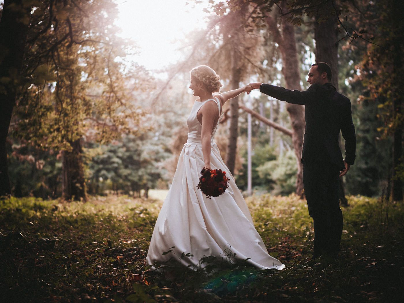 Bride and groom dancing in the woods, beautifully backlit by the early evening light - wedding photos Schloss Saareck