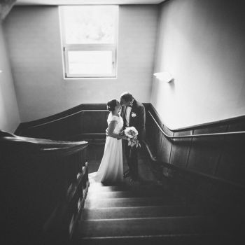 Küssendes Brautpaar auf der Treppe im Schlosshotel Kronberg, Braut im roten Kleid, Hochzeitsfoto einer Winterhochzeit, mit Reflektionen der Weihnachtsdekoration - Hochzeitsfotograf Taunus Brautrausch