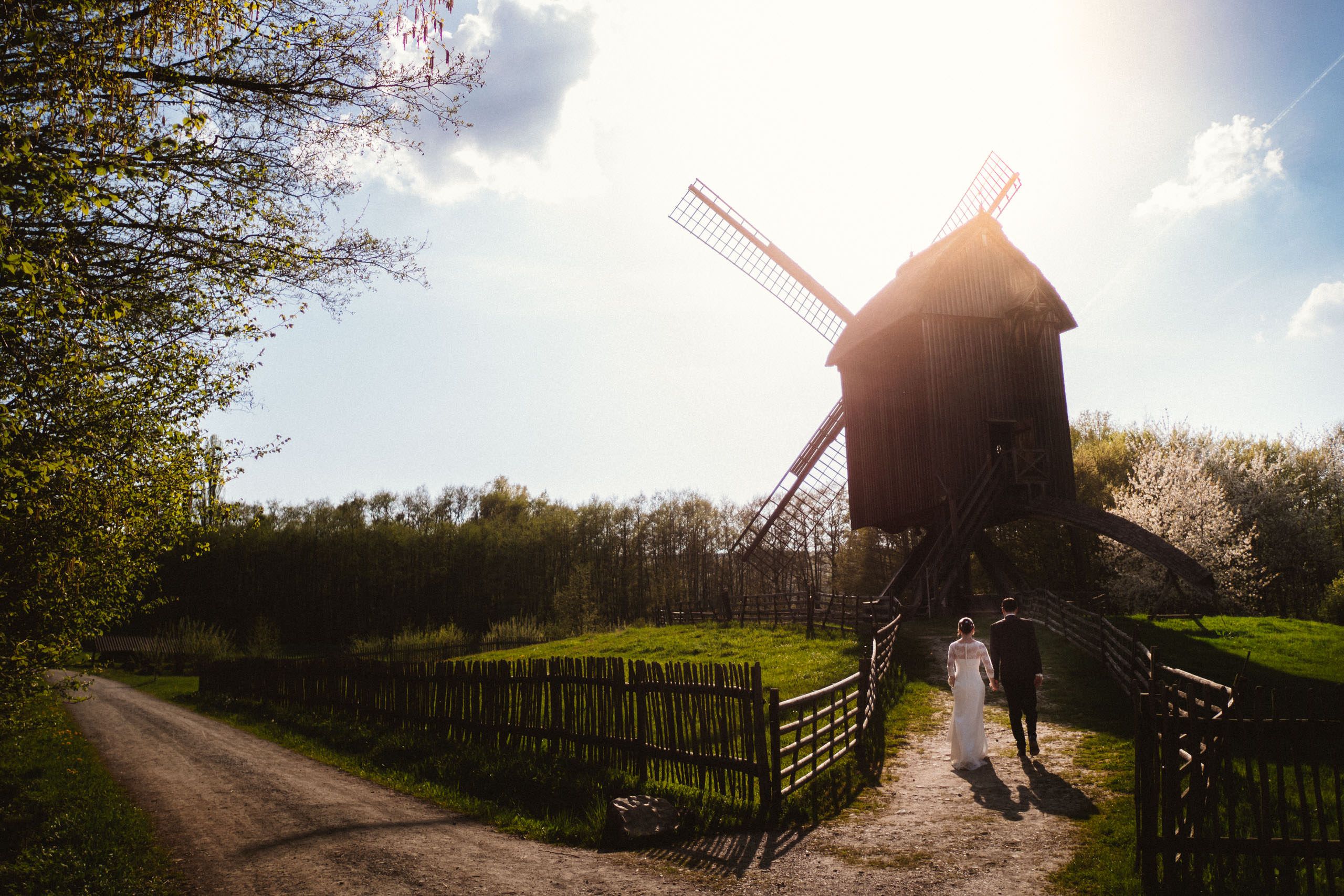 Brautpaar läuft im Licht der Nachmittagssonne auf eine Windmühle zu - Hochzeitsfotograf Taunus Brautrausch