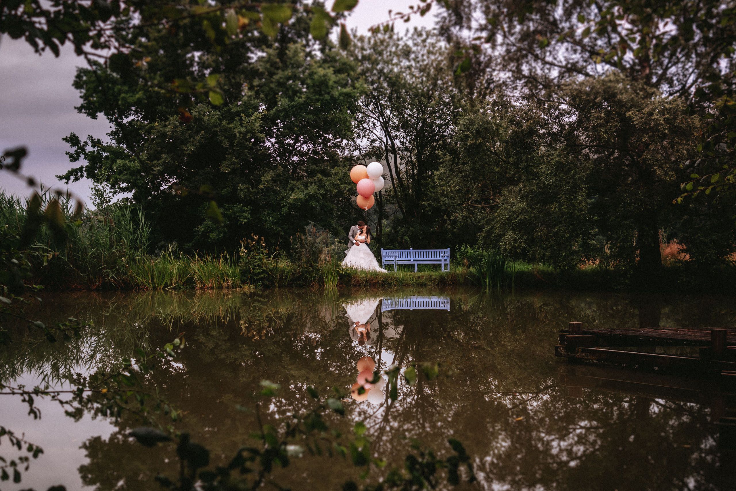 Hochzeitsfoto von Brautpaar mit Ballons am Teich von Hofgut Georgenthal - Hochzeitsfotograf Taunus Brautrausch