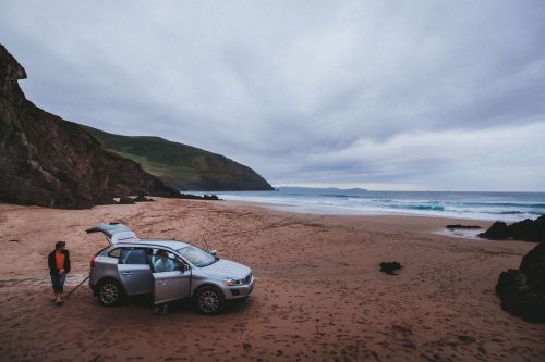 Mietwagen (Volvo XC60) auf dem Sandstrand am Slea Head, County Kerry, im Hintergrund der Atlantik
