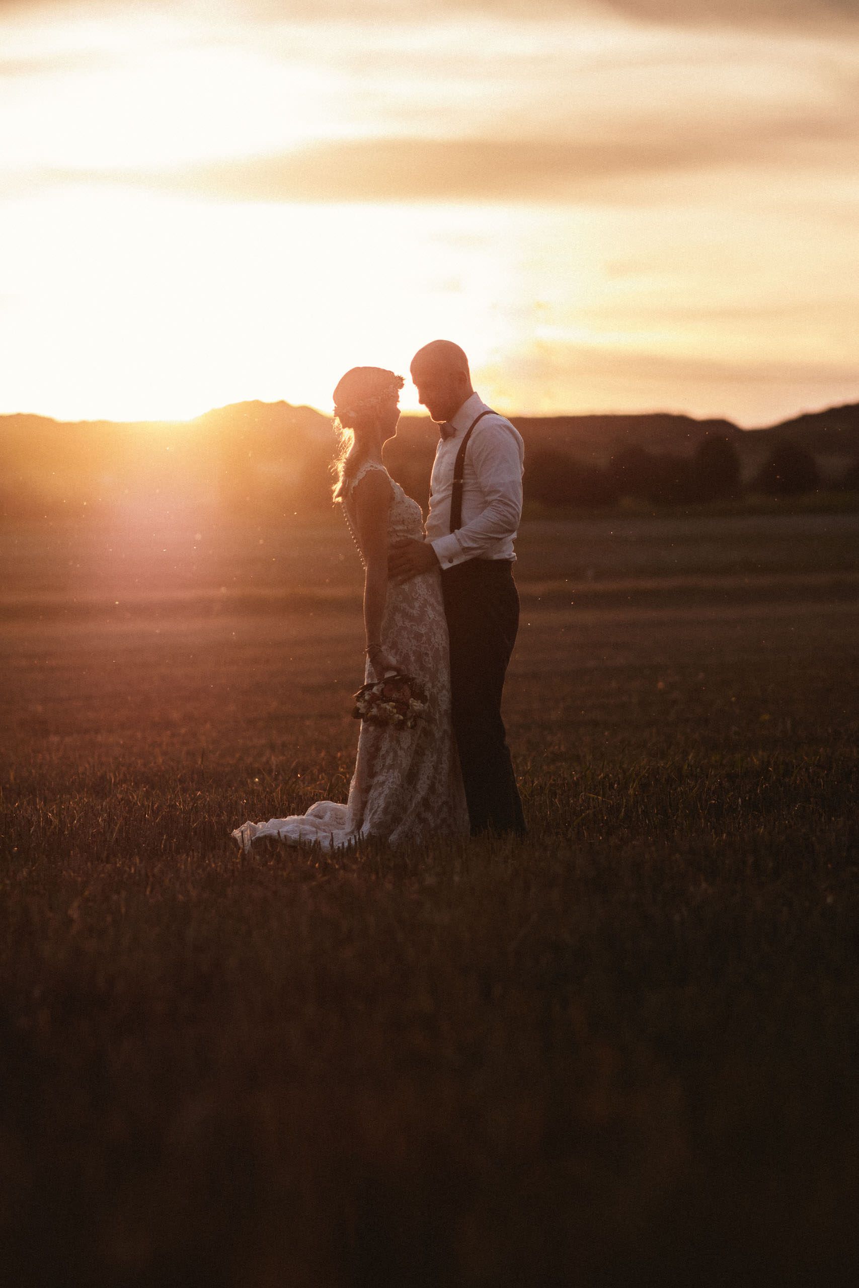 Brautpaar stehend auf Feld im Sonnenuntergang - Hochzeitsfotograf Taunus Brautrausch