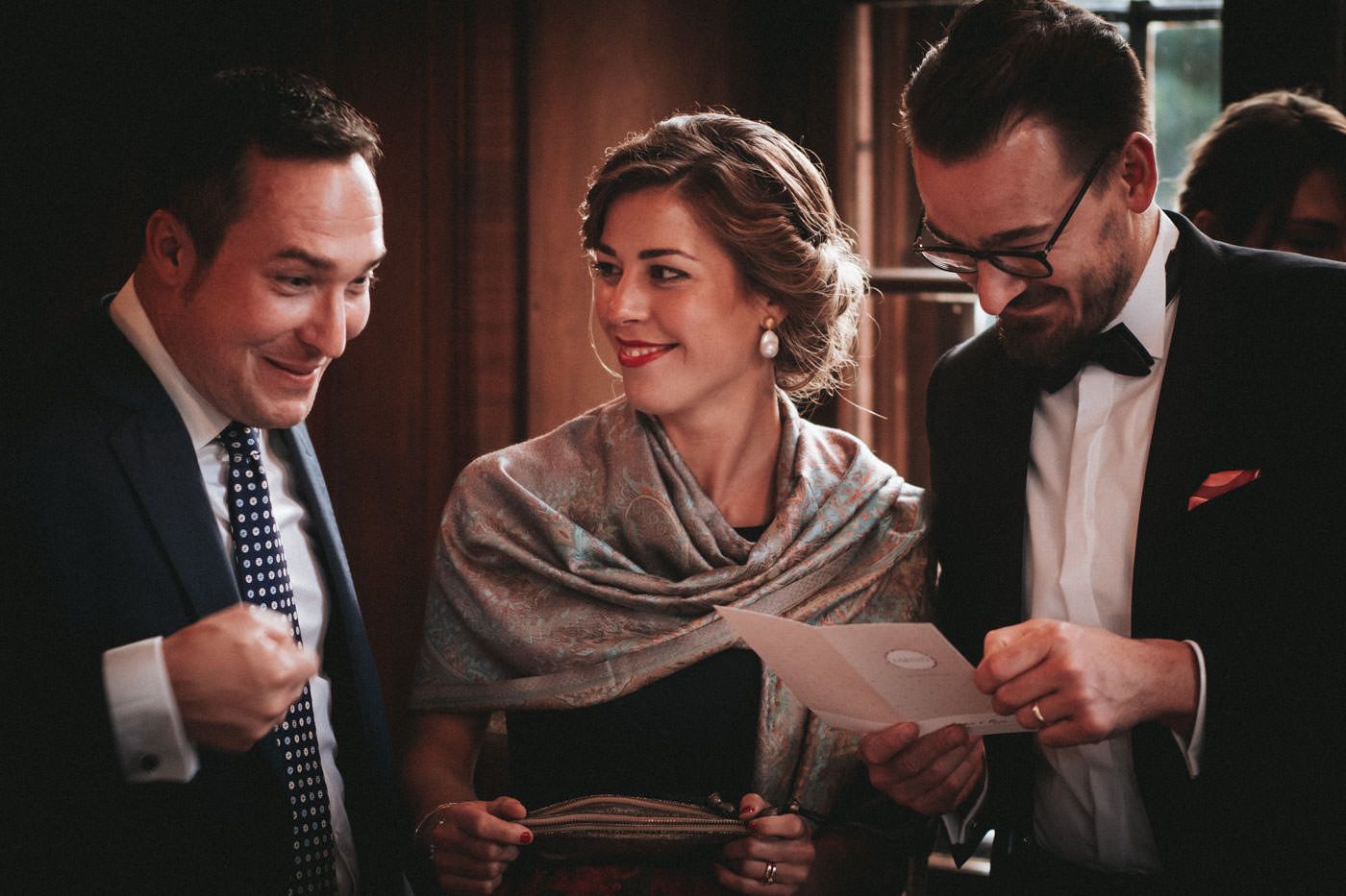 Happy wedding guests - two men and a beautiful woman in their middle studying the wedding menu